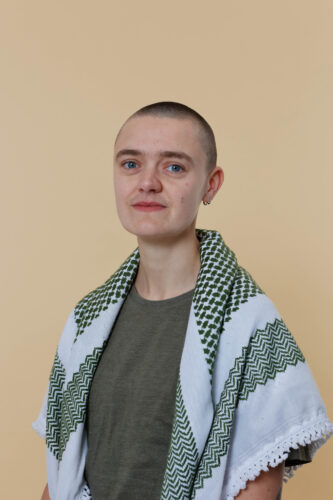 Portretfoto van Utrecht BIJ1 kandidaat Welmoed Yonas. Hen draagt een groen met witte keffiyeh.